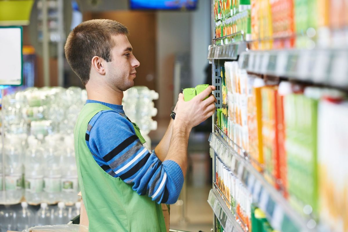 layout degli scaffali nei supermercati: ragazzo durante la risistemazione 