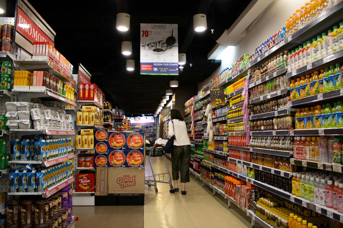 Donna che cammina tra scaffali di supermercato durante la spesa