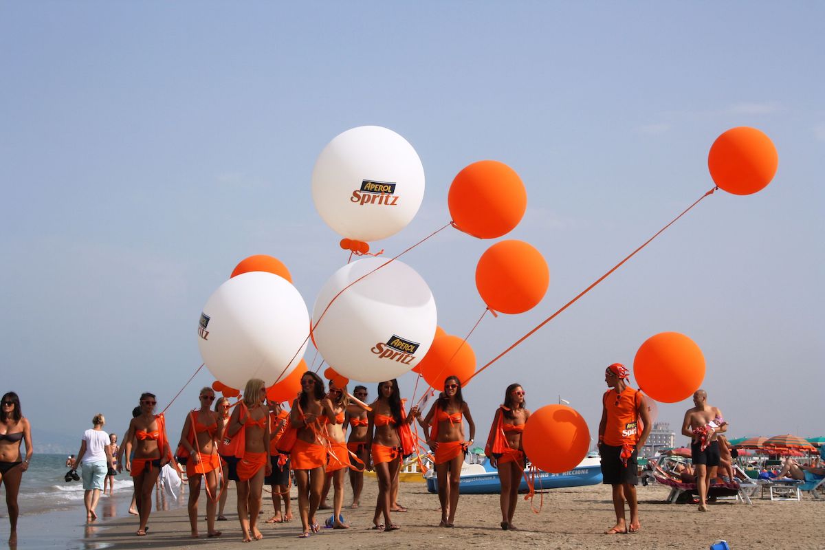 esempio di promozione per attirare i clienti: hostess e promoter per aperol spritz in spiaggia. 